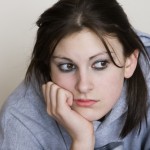 Studk in her head: Bored teenager looking depressed, with a grey background