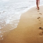 Taking steps: A young woman walking on the sand.