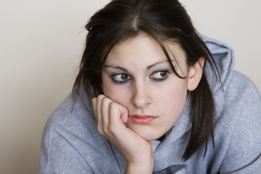 Studk in her head: Bored teenager looking depressed, with a grey background