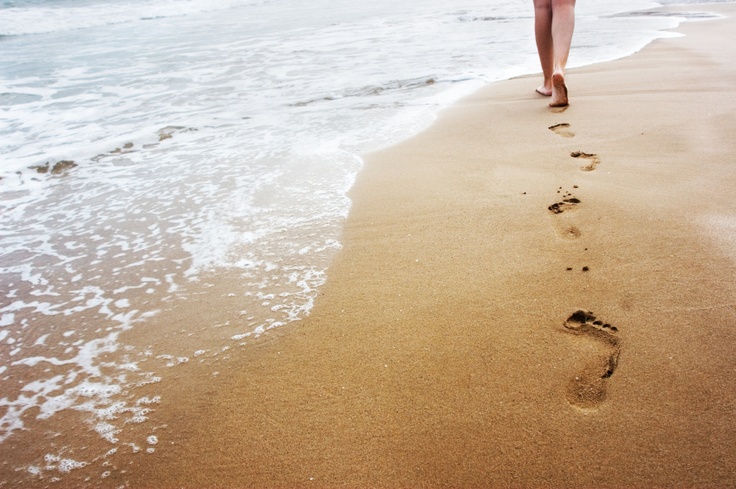 Taking steps: A young woman walking on the sand.