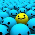 A bunch of blue frowny faces and one yellow smiley face